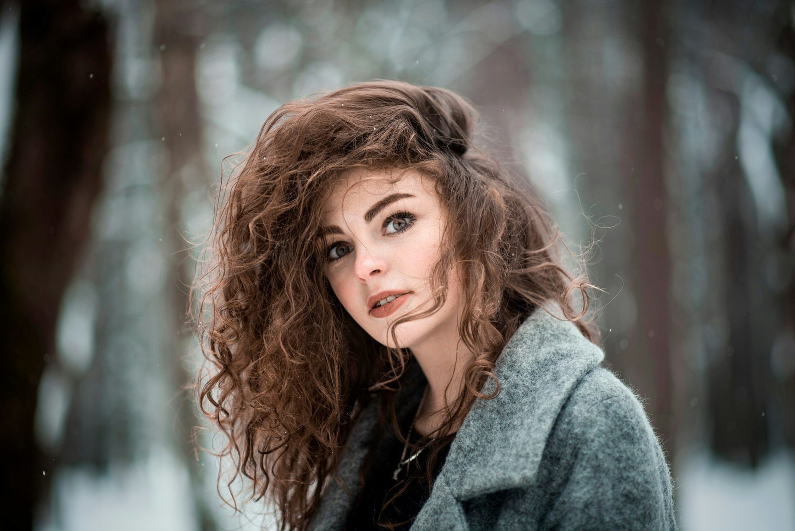 a woman with curly hair standing in the snow