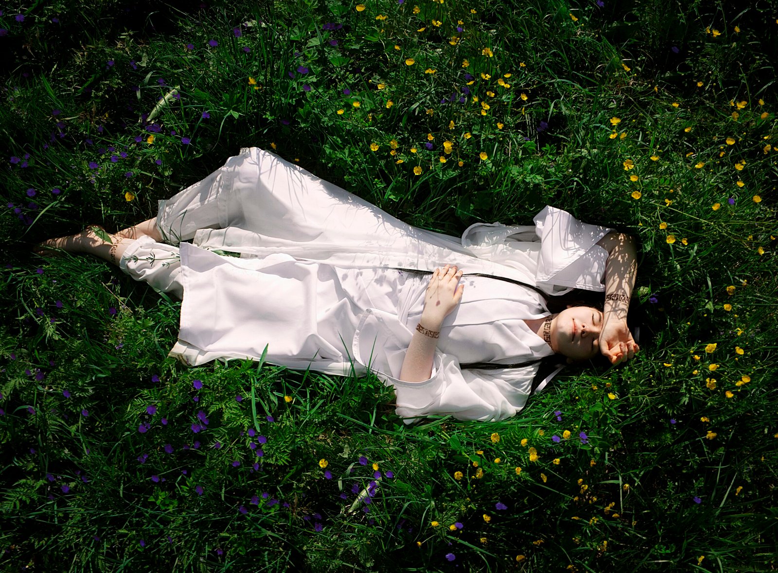 a woman in a white dress laying in a field of flowers