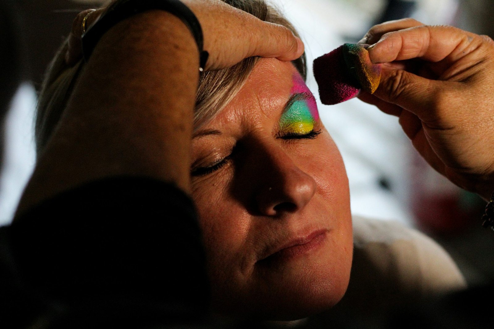 Woman receiving colorful eye makeup application