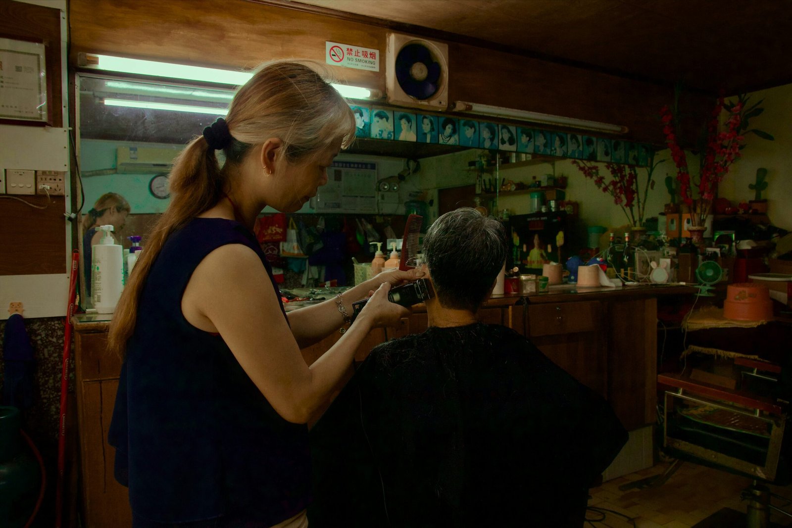 Woman cutting man's hair in a barber shop.