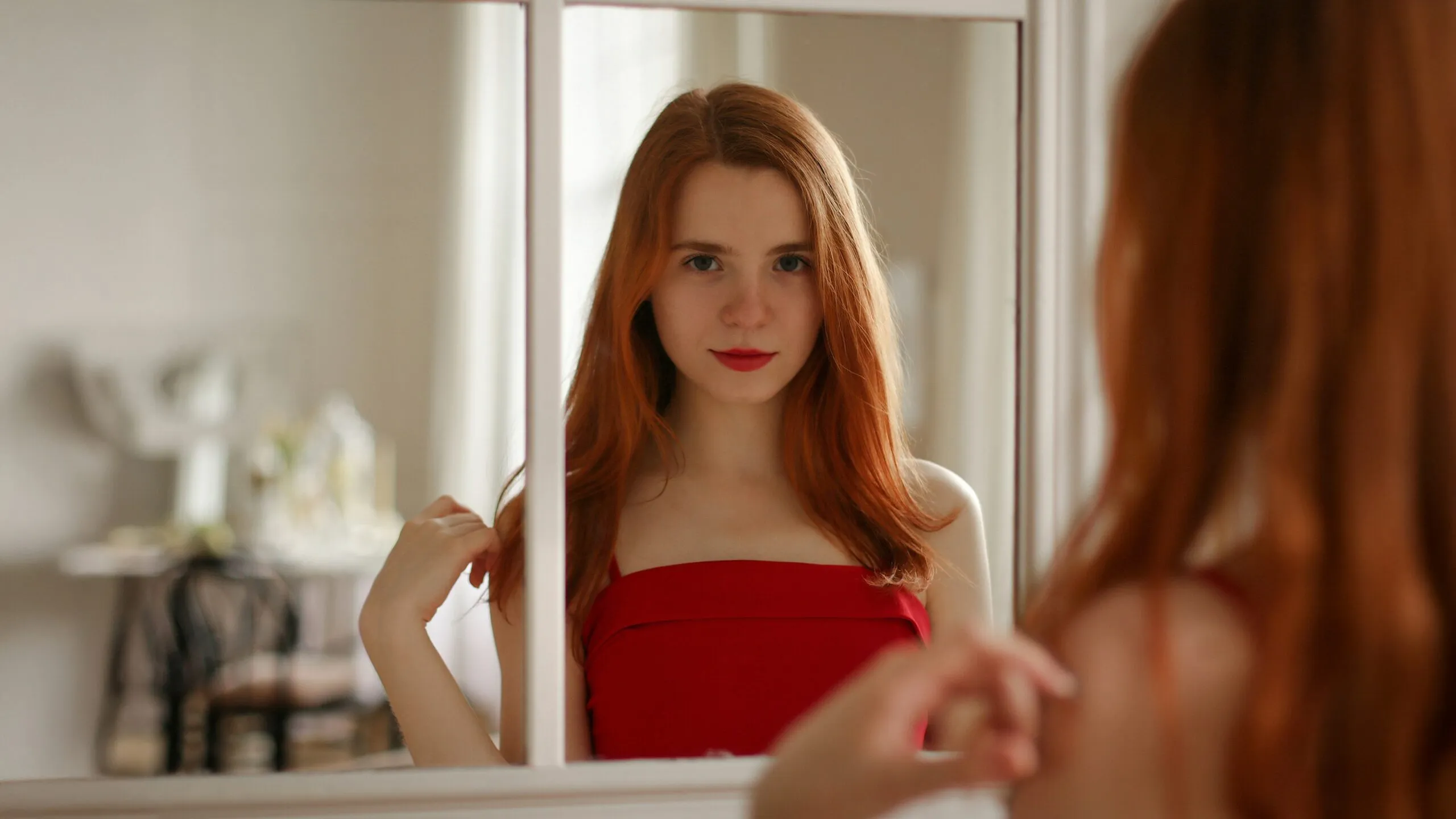 Young woman with red hair looking in mirror