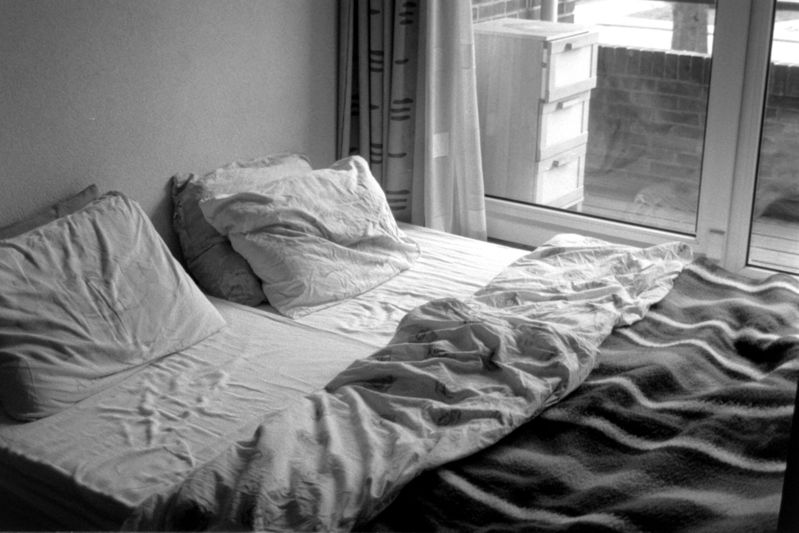A bed is unmade near a window.