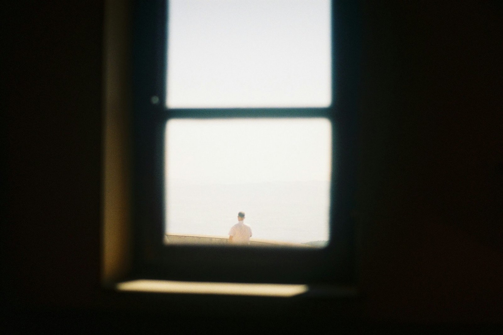 Person standing by the ocean seen through window