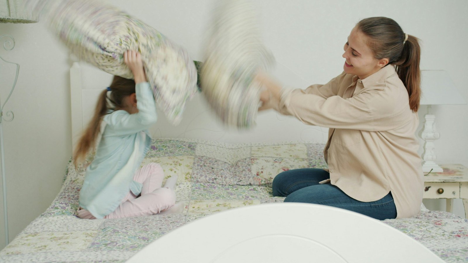 Mother and daughter having a pillow fight on bed