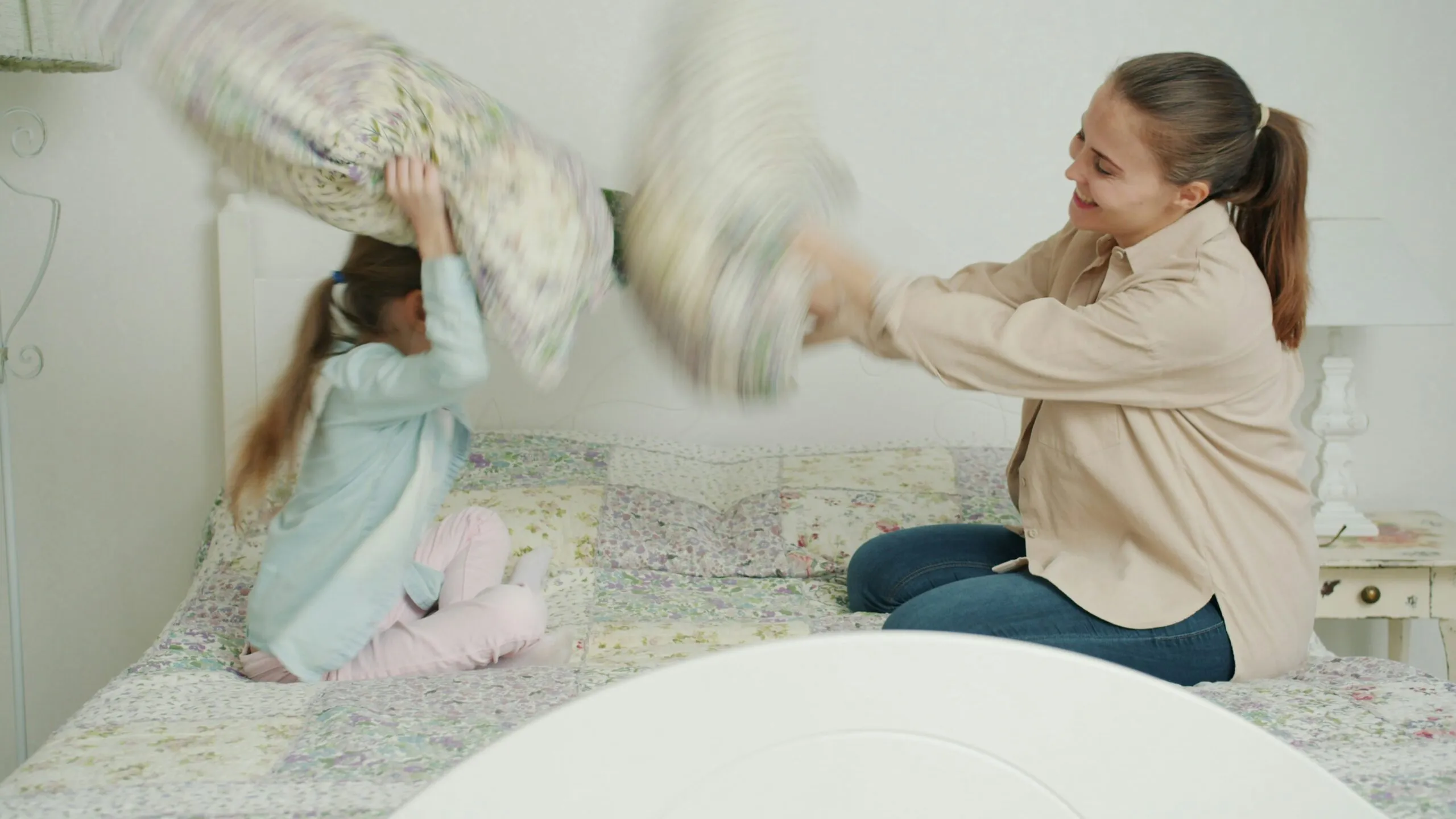 Mother and daughter having a pillow fight on bed