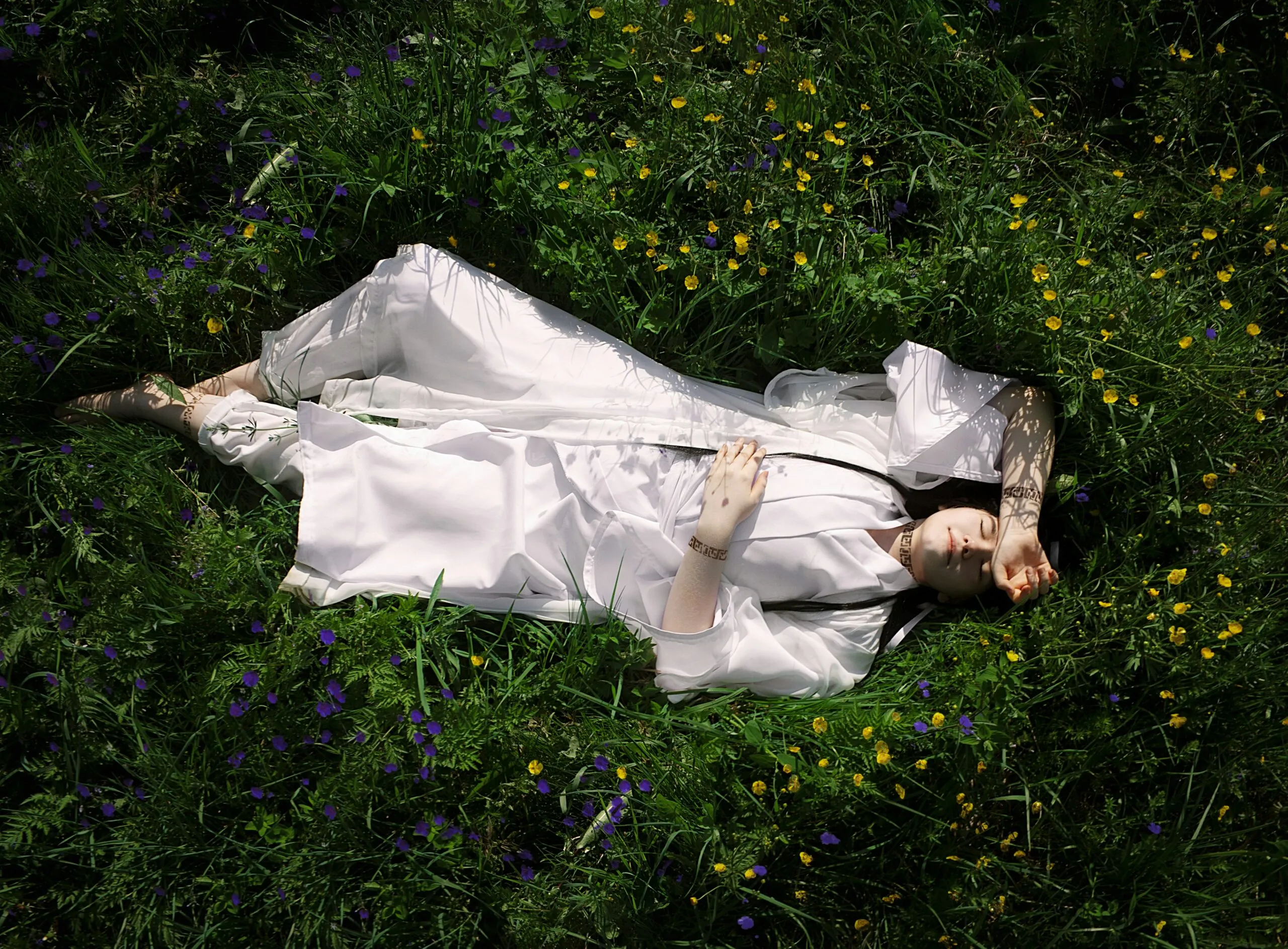 a woman in a white dress laying in a field of flowers