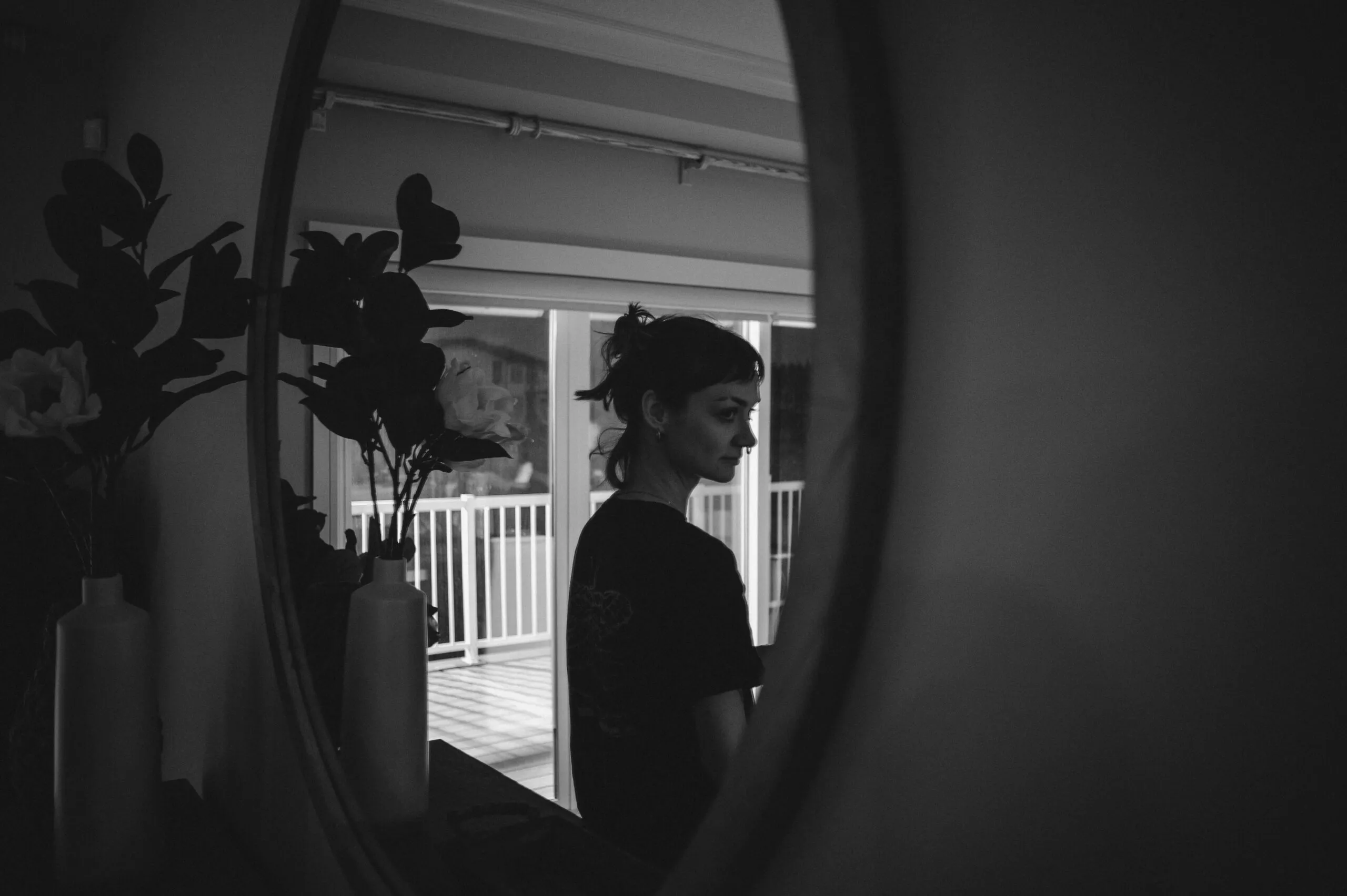Woman's reflection in an oval mirror indoors