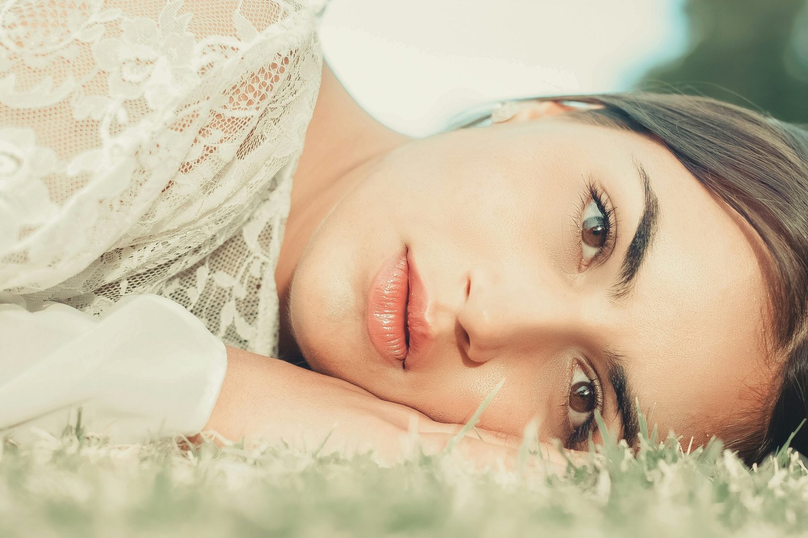 woman in white lace shirt lying on white textile