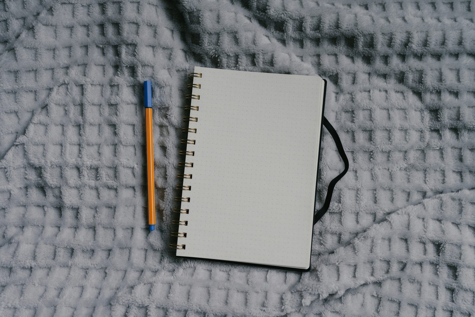 Notebook and pen sit on a textured surface.