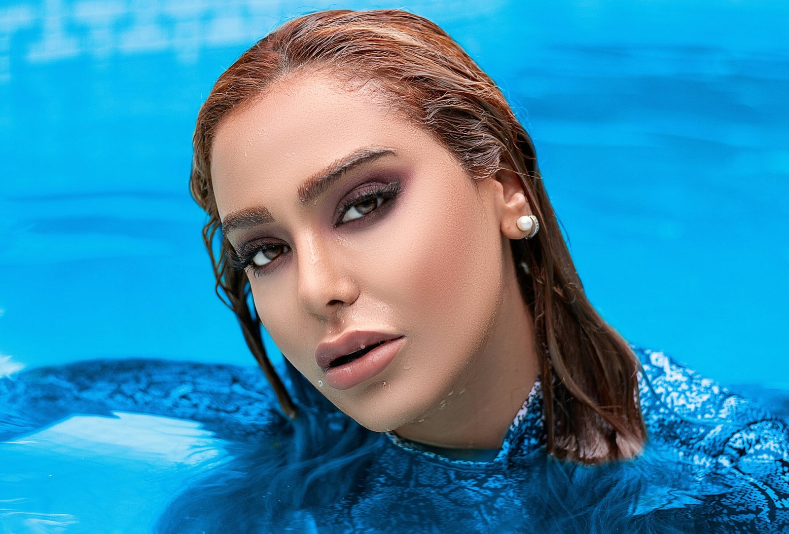 a woman in a blue dress is floating in a pool