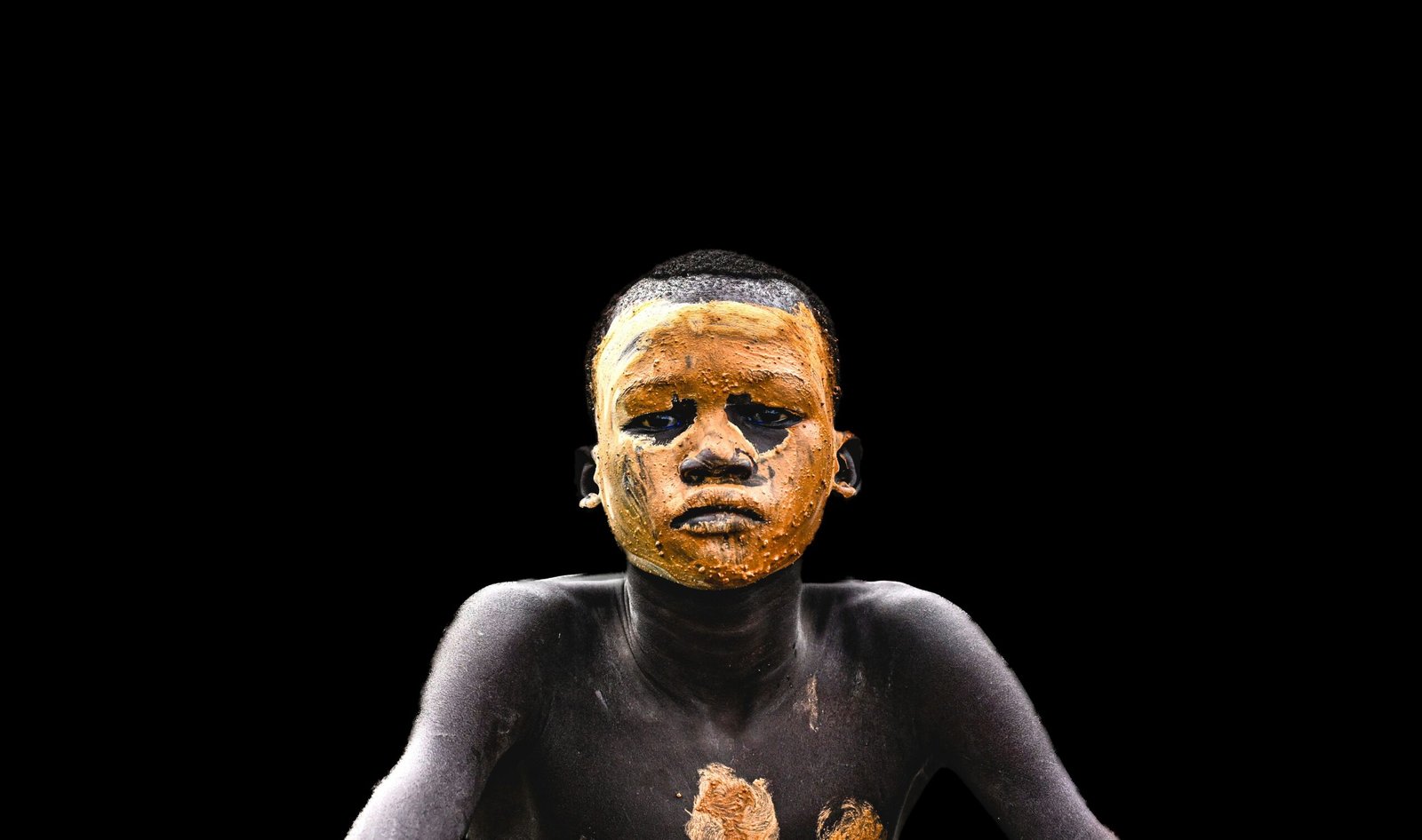 A person covered in muddy pigment.