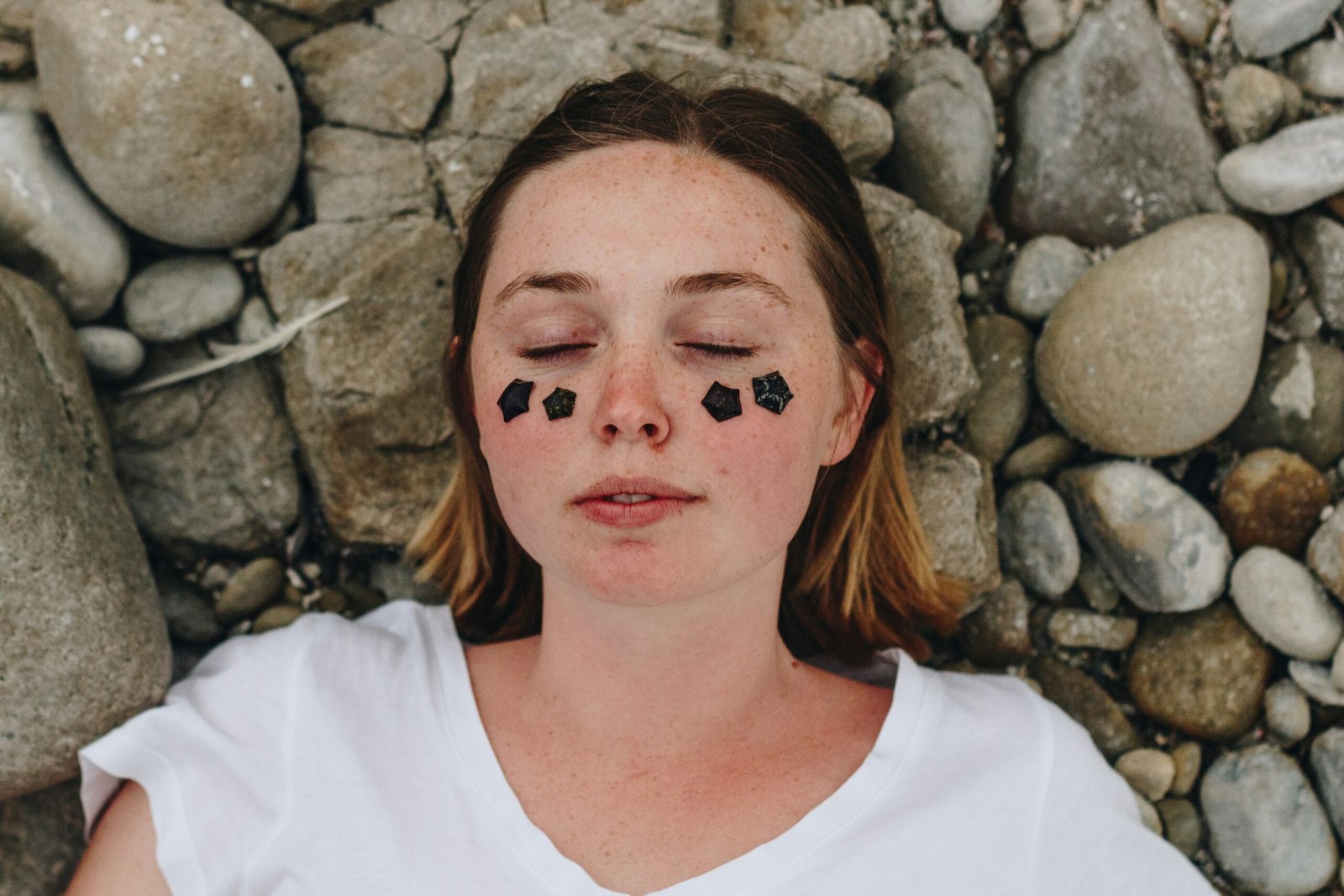 a woman laying on rocks with her eyes closed