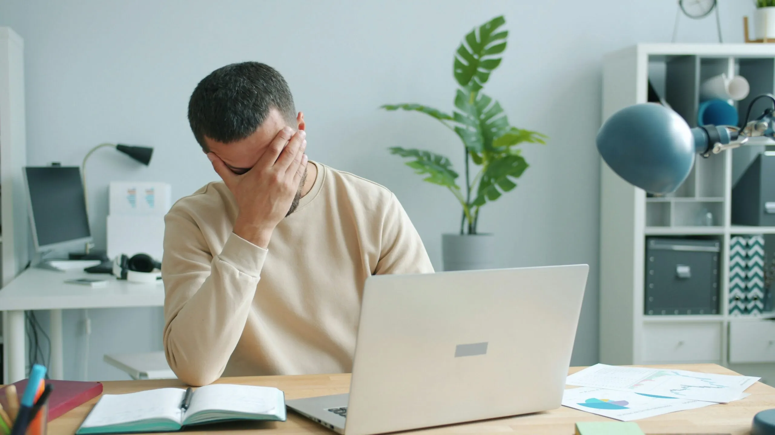 Man rubbing his face in front of laptop.