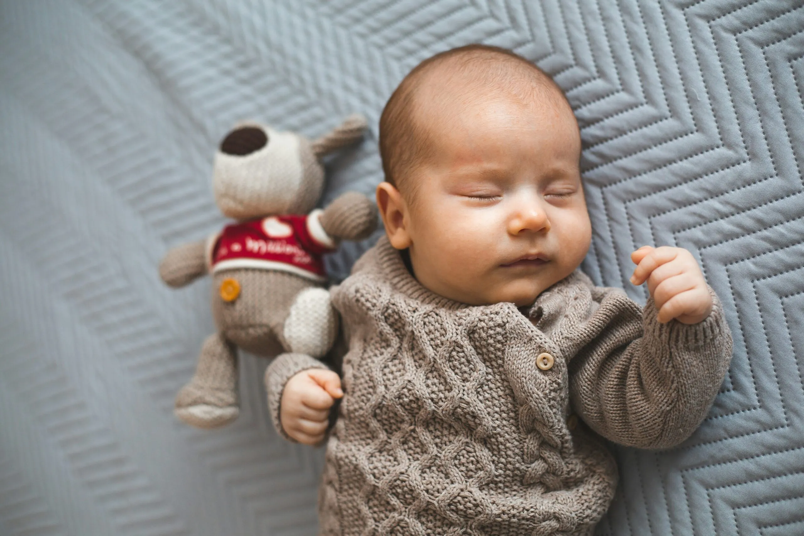 A baby sleeps peacefully next to a stuffed toy.