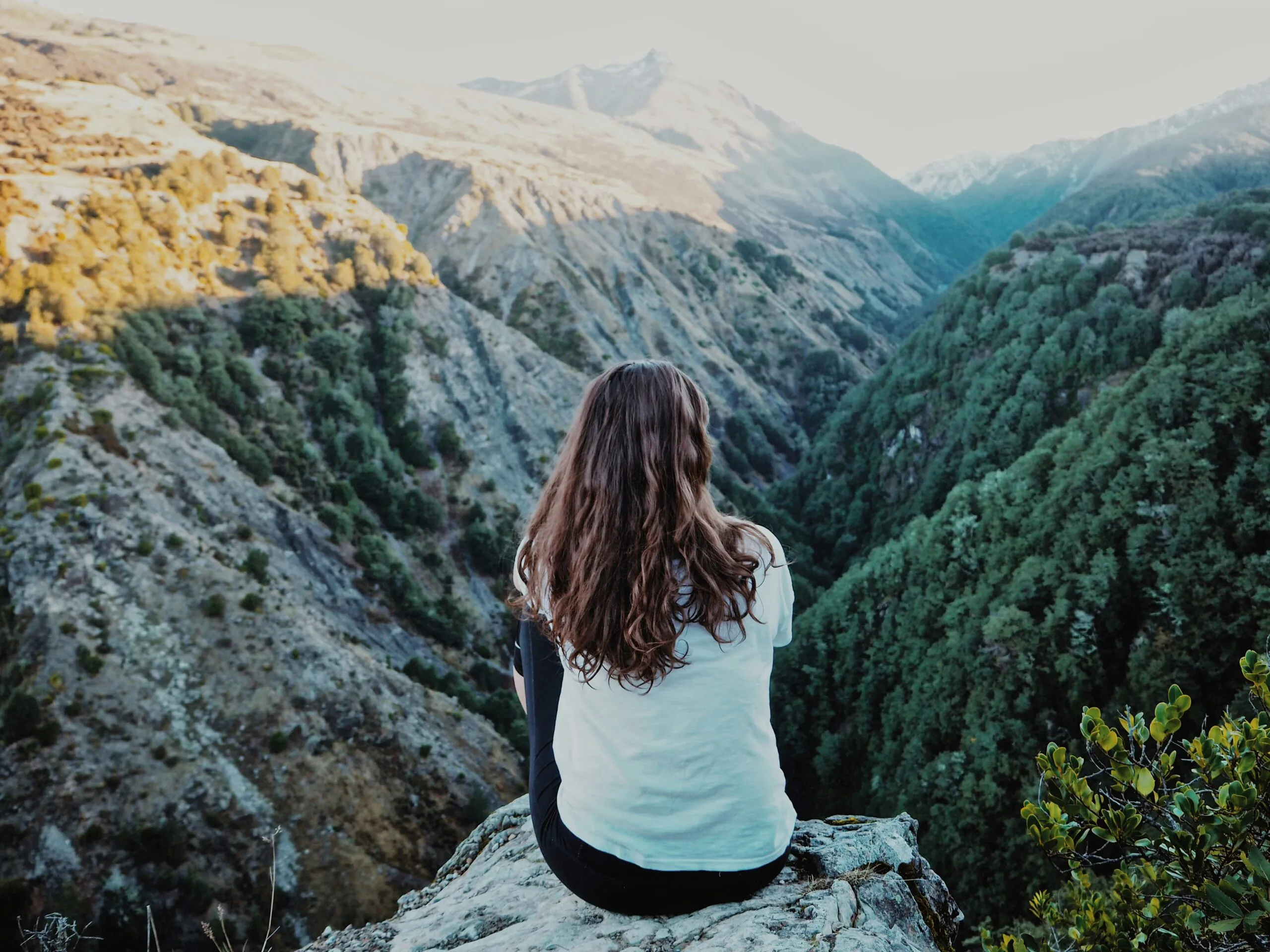 woman sitting on mountain peak