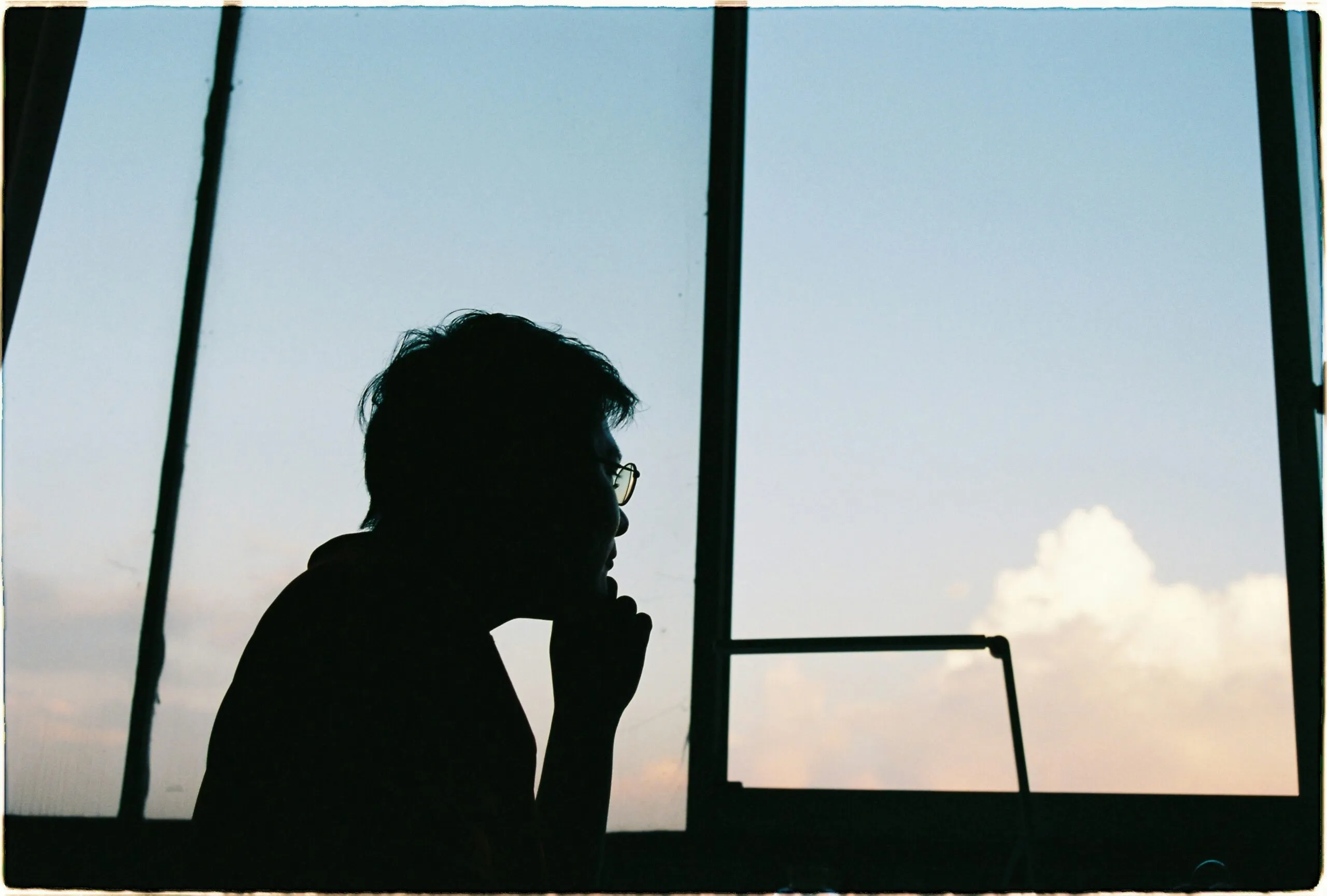 Silhouette of a person looking out window at the sky.