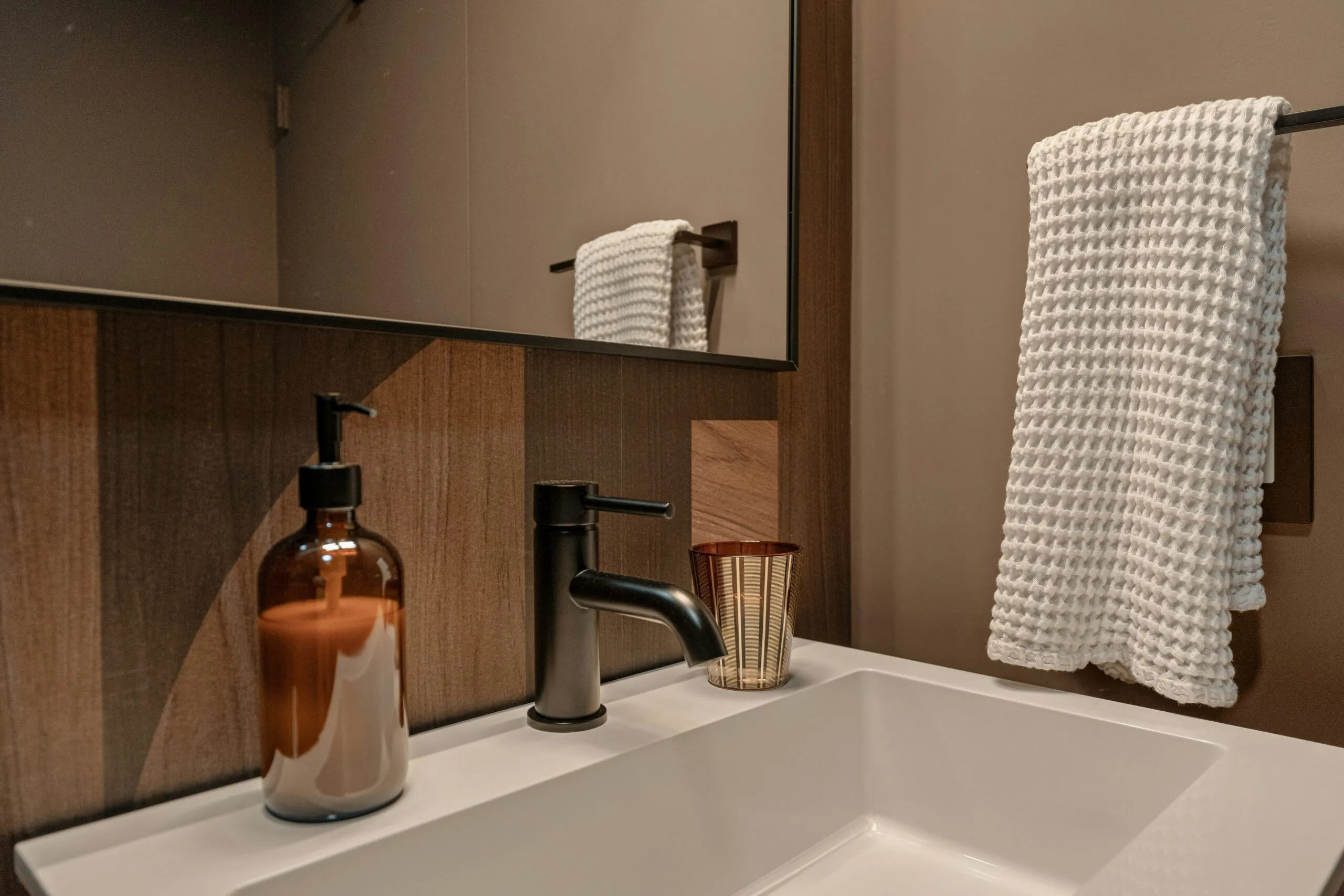 Modern bathroom sink with soap dispenser and towel.