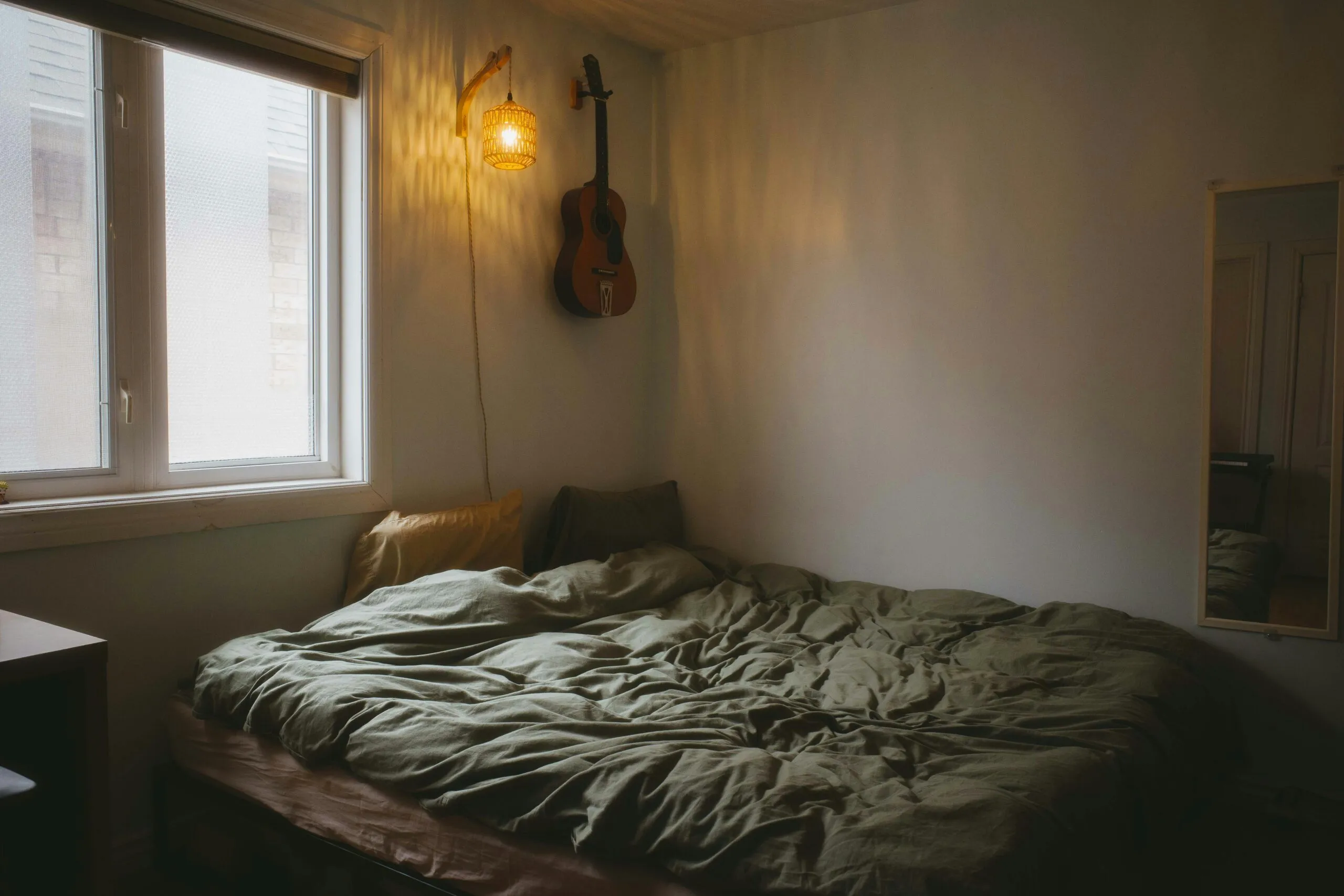 A cozy bedroom with a guitar and bed.