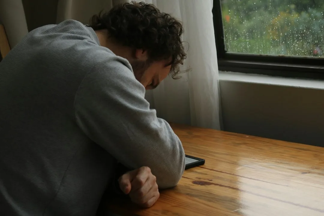 Man is looking at a screen with his head down.