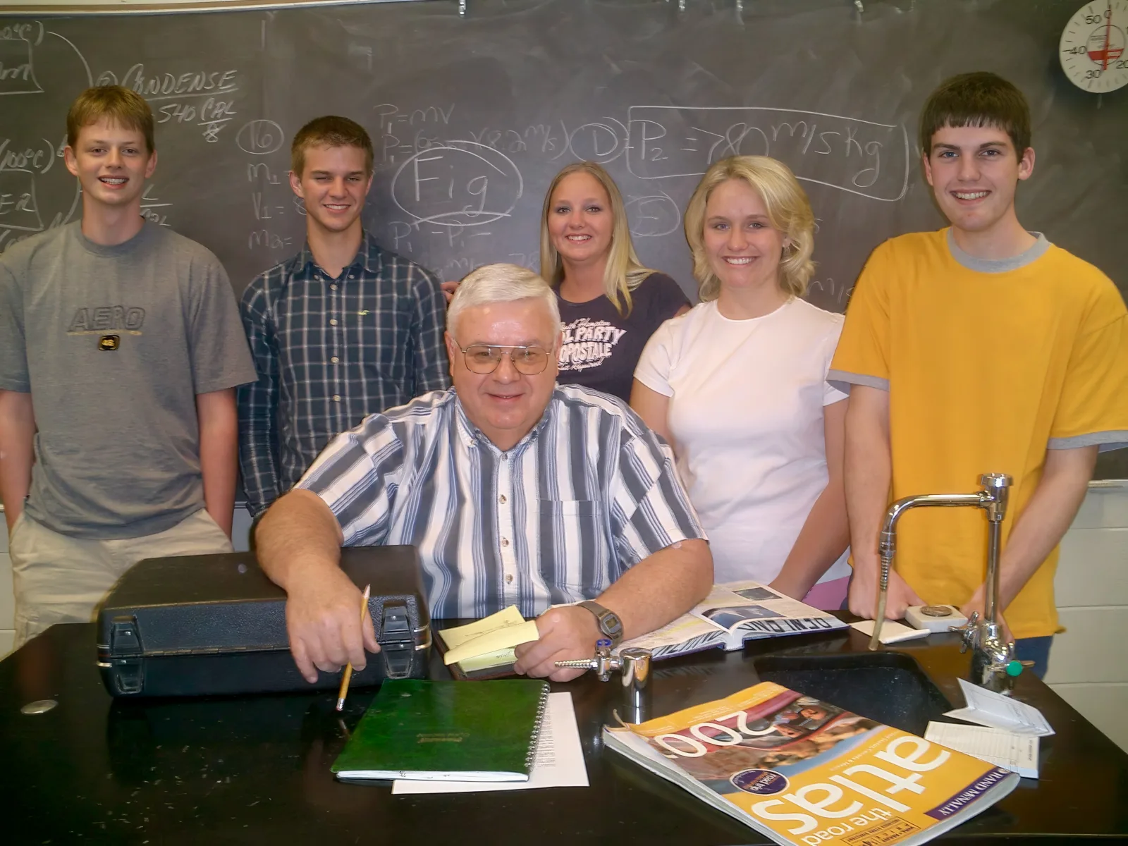 A public high school teacher surrounded by students in a classroom in the United States