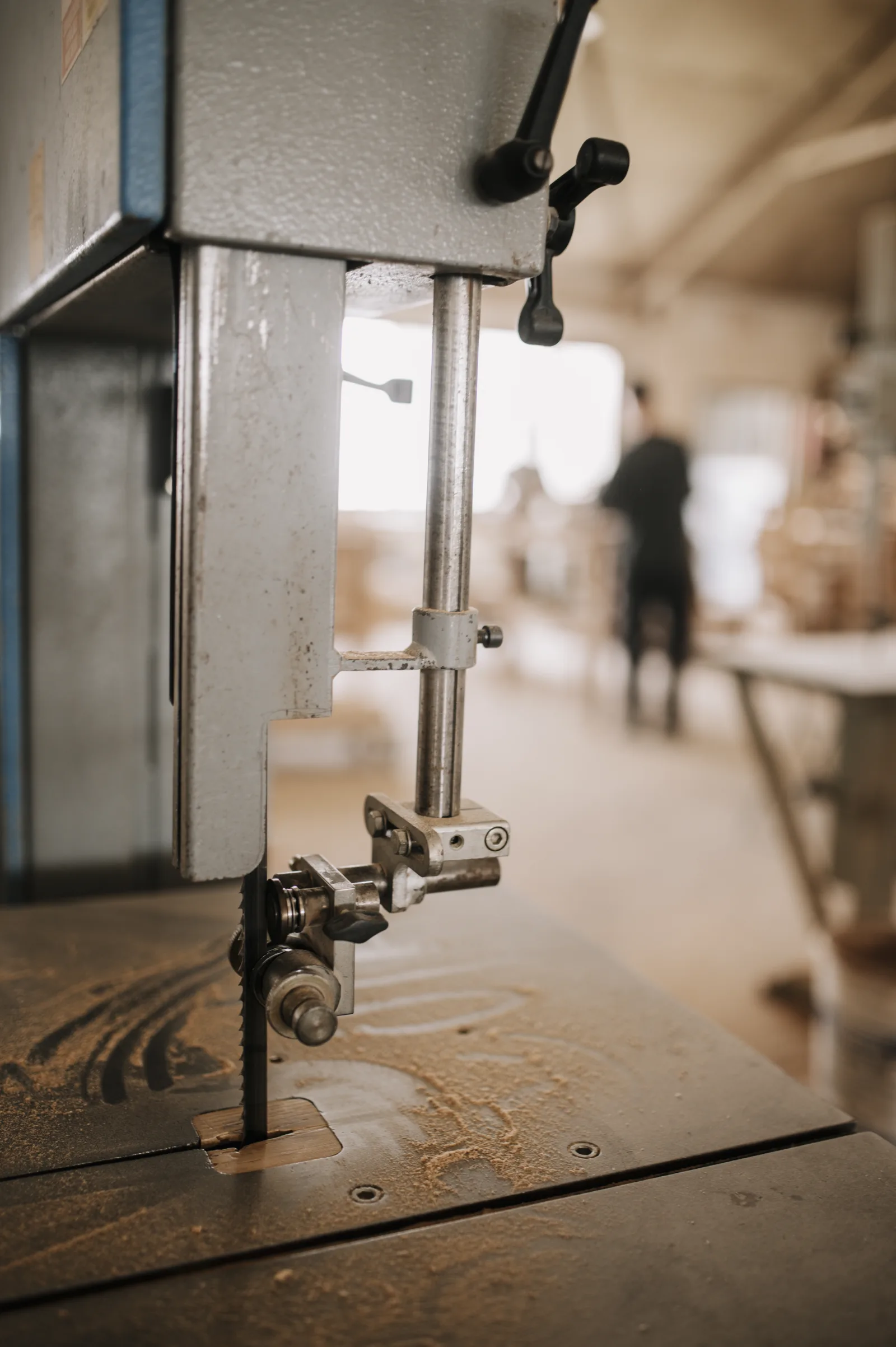 Band saw in a woodworking workshop during a project with craftspeople working in the background