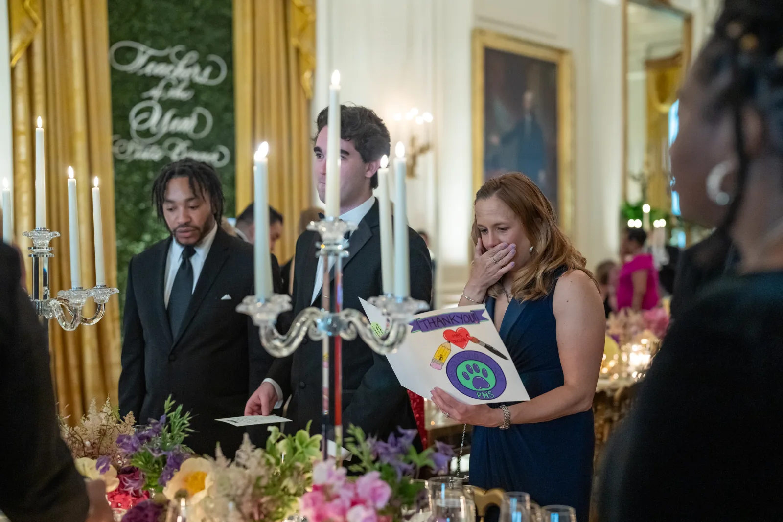 Elizabeth Duclos, New Hampshire's Teacher of the Year, reacts as she reads a thank you card from students, teachers and leadership at her school as she arrives at her seat at the Teachers of the Year State Dinner, Thursday May 2, 2024, in the East Room of the White House. (Official White House Photo by Cameron Smith)