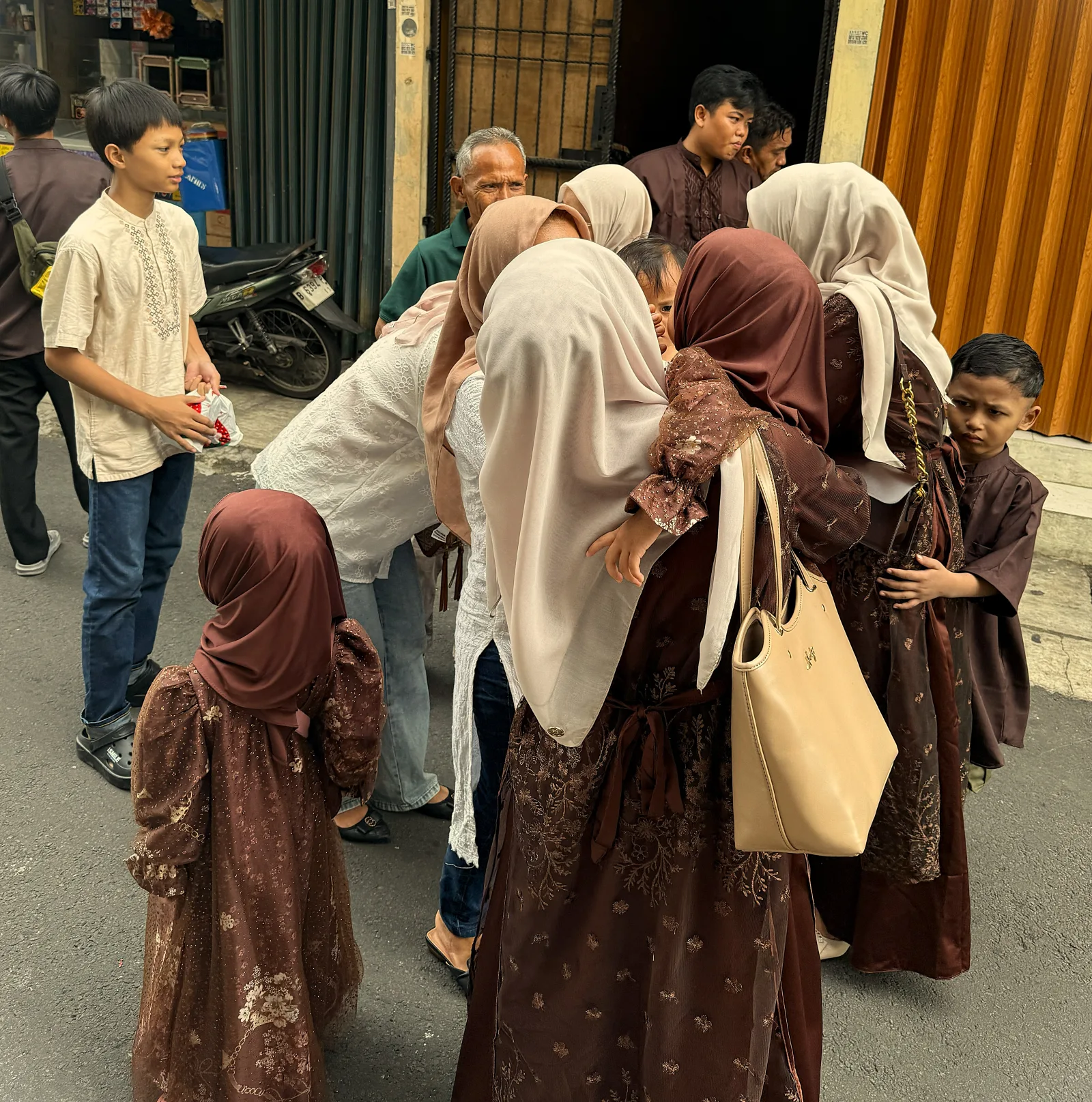 A tender moment unfolds as family members gather closely, exchanging warm embraces and greetings. Surrounded by soft earth tones and modest attire, the scene reflects the essence of Ramadan a time of forgiveness, connection, and heartfelt togetherness.