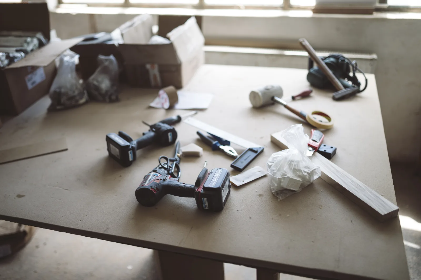 Workbench cluttered with tools, screws, and materials during a DIY project in a bright workshop