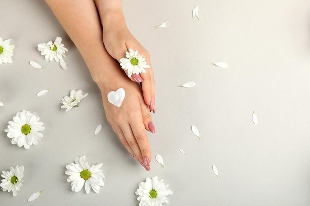 Concept of hand care on gray background with flowers