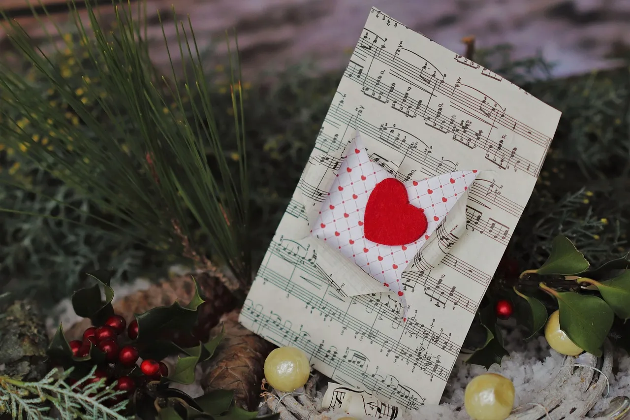 sheet music, love letter, red heart, envelope, music notes, romantic, christmas, holiday decor, winter, pine, berries, handmade, melody, affection, greeting card, festive, cozy, rustic, paper art, creativity, musical, romance, christmas card, love message, season, card