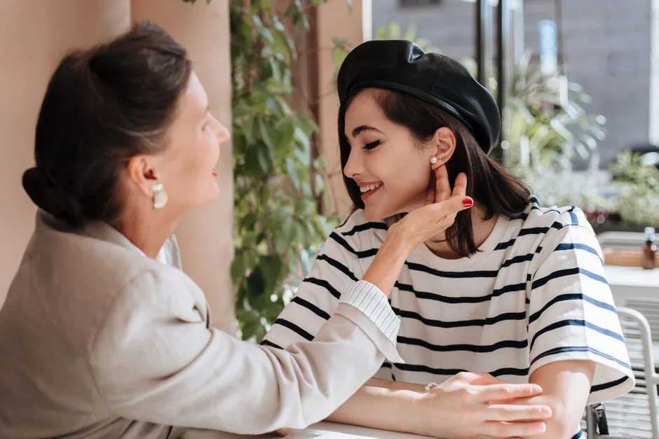 A heartwarming moment of two women smiling and chatting at an outdoor cafe.