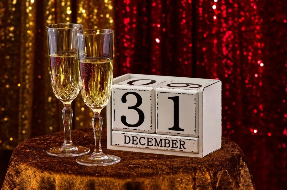 Elegant New Year's Eve table setting with champagne glasses and December 31 calendar block.