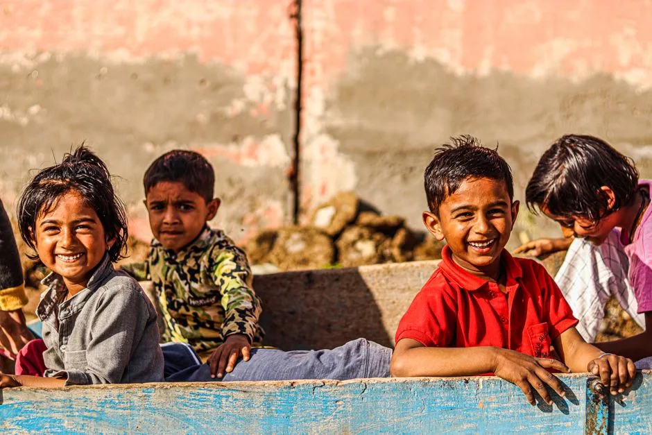 Children laughing and playing outdoors in bright sunlight, enjoying a joyful moment together.