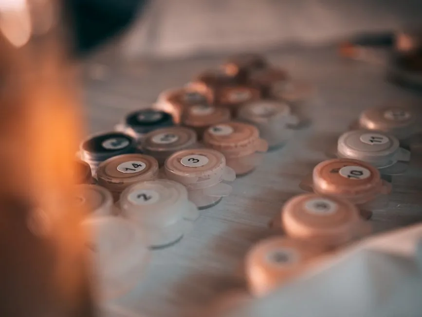 Artistic close-up of numbered paint pots on a table, ideal for painting by numbers enthusiasts.