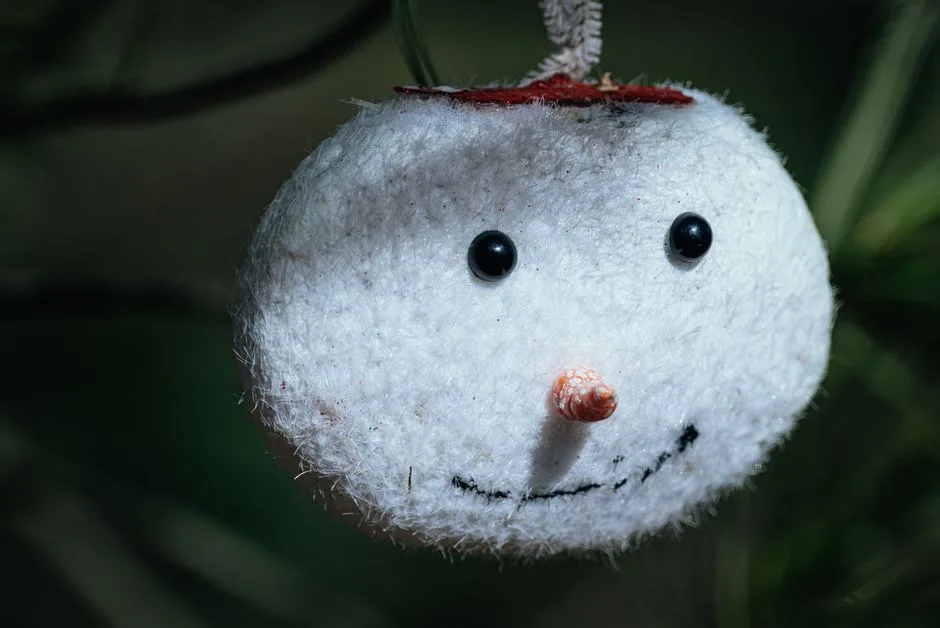 Close-up of a handmade snowman ornament hanging on a tree, festive and cute.