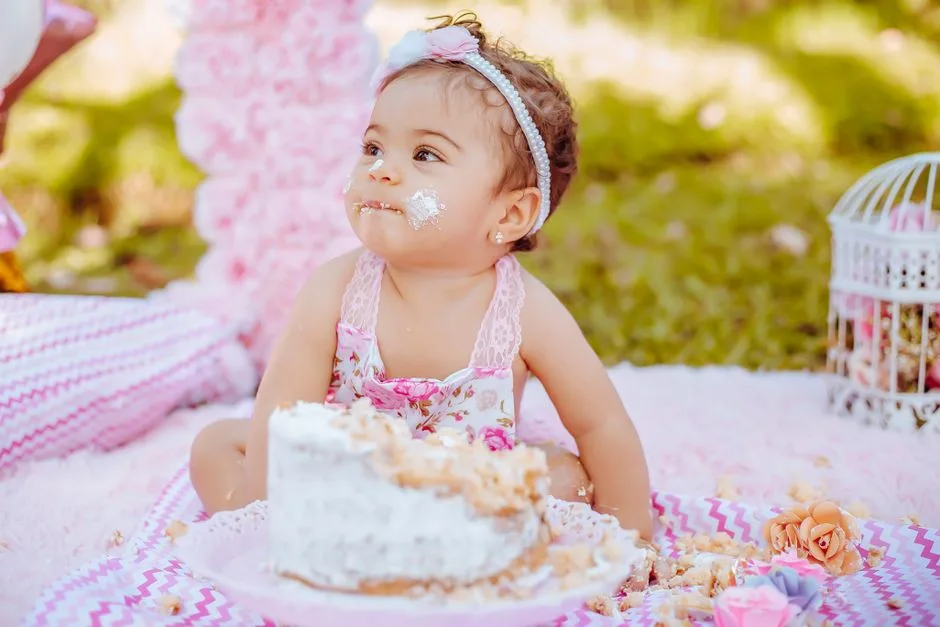 Charming scene of a baby's first cake smash outdoors with a pastel theme and floral decor.
