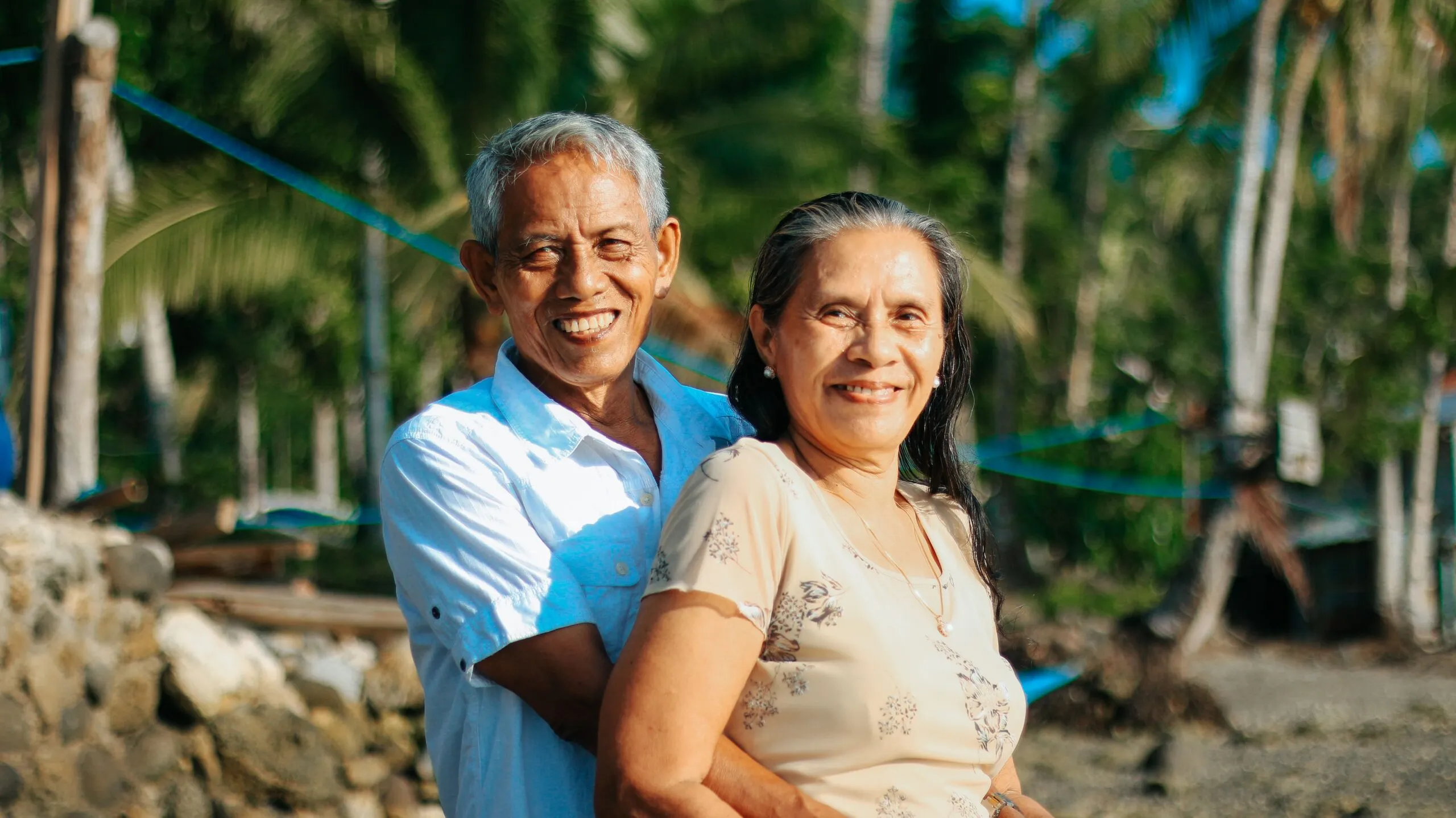 A happy senior couple embracing and smiling at the beach, capturing love and togetherness.