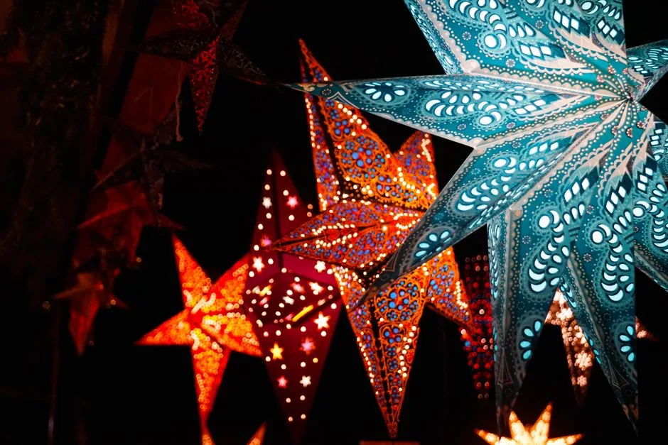Colorful illuminated star-shaped lanterns glowing brightly against a dark night sky.
