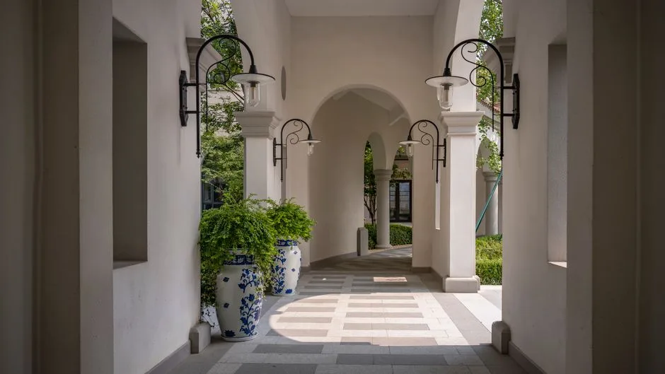 Arched corridor in luxury Mediterranean villa with elegant lighting and greenery.