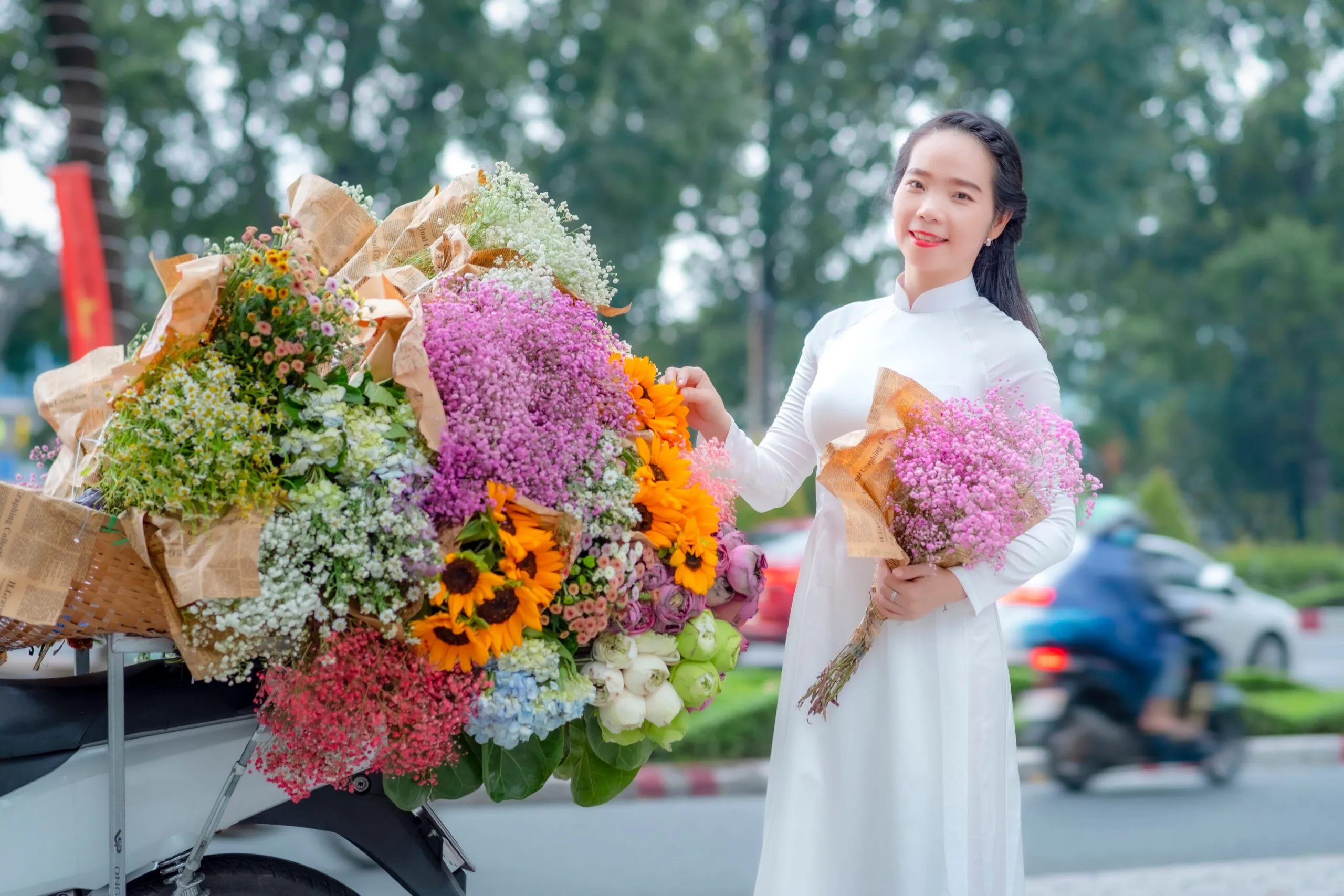 A woman in a white dress happily holding a bouquet of vibrant flowers outdoors.