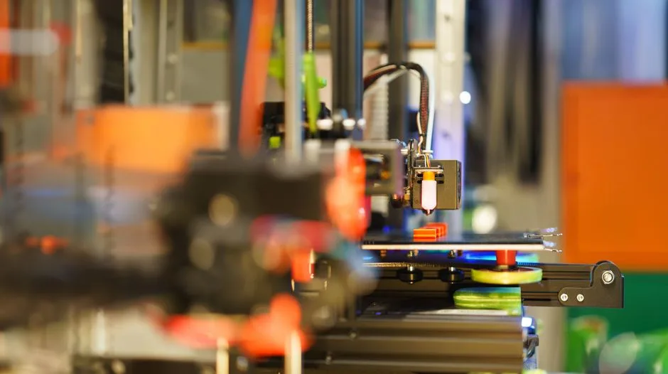 Detailed view of a 3D printer in action, producing a colorful prototype.