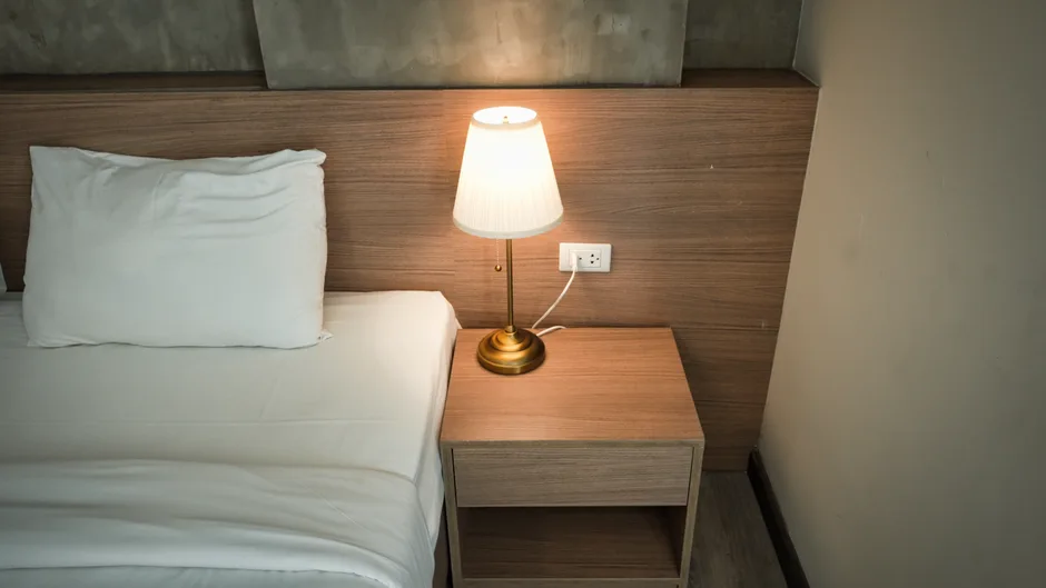 Elegant bedroom setup with a lamp on a wooden nightstand, creating a cozy ambiance.