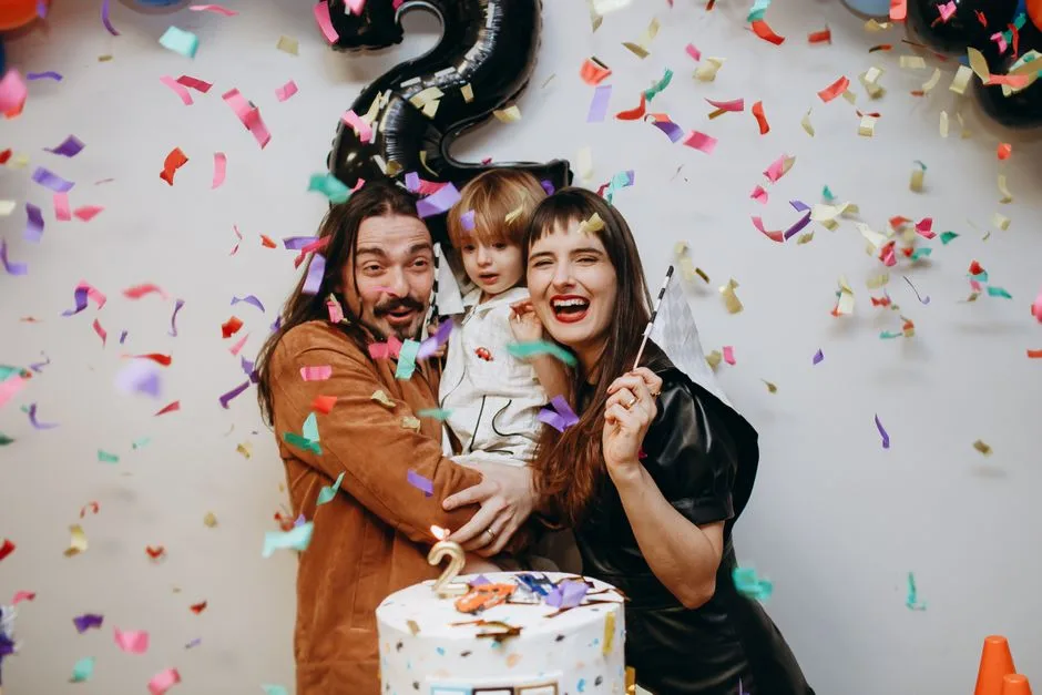 Family celebrating a birthday indoors with confetti and a cake, creating joyful memories.