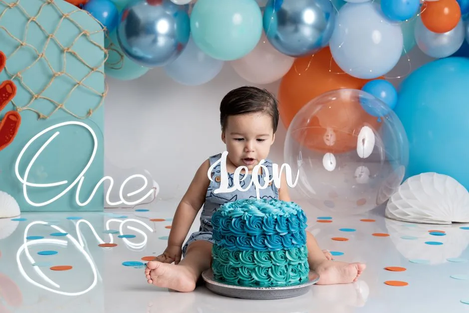 Cute baby celebrating first birthday with colorful cake and balloons.
