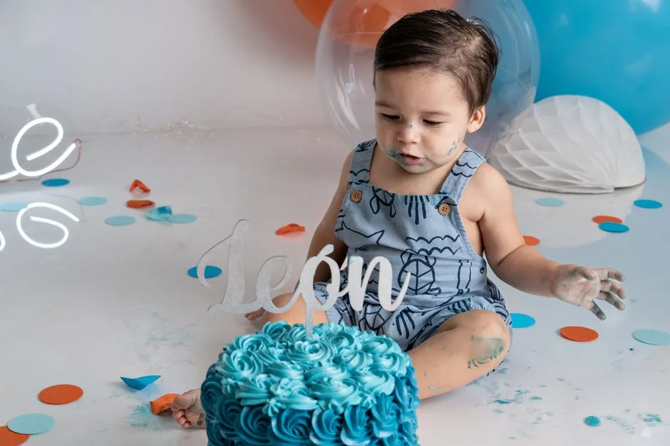 Cute baby enjoying a colorful cake smash during first birthday celebration.