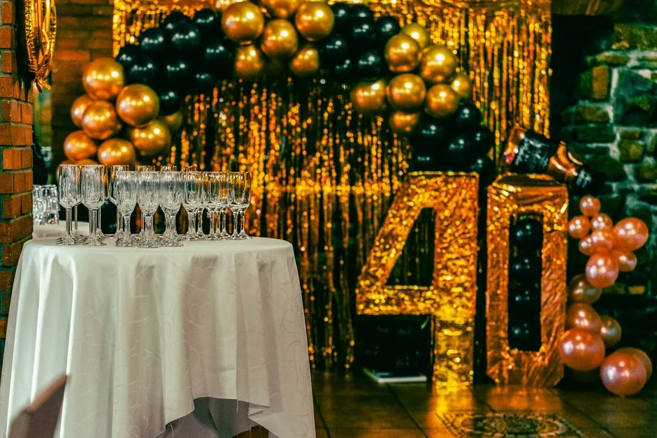 Chic 40th birthday party setting with champagne flutes, balloons, and gold glitter backdrop.