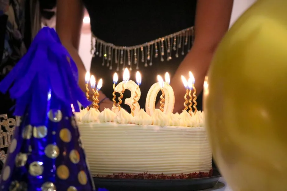 Close-up of a birthday cake with '30' candles at a festive celebration.