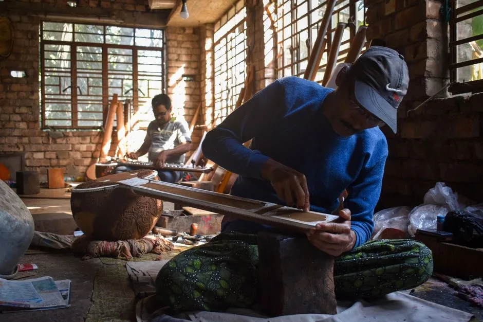 Artisans in Kolkata workshop creating intricate traditional musical instruments.