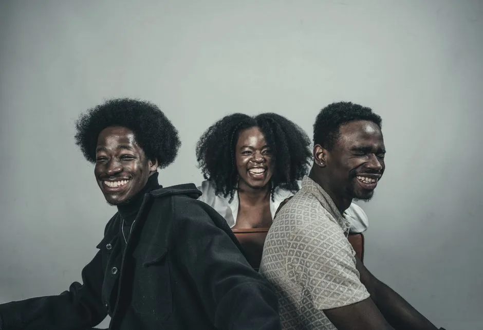 A trio of friends smiling and enjoying a great time indoors. Their happiness is contagious.