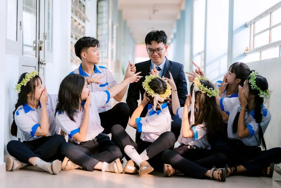 Group of happy students in uniform celebrating with their teacher in a hallway.